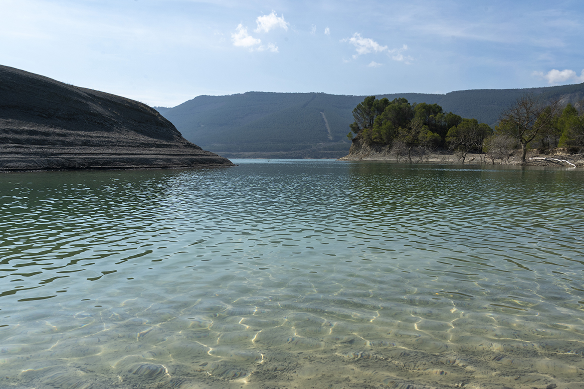 Embalse de Yesa con aguas cristalinas y montañas boscosas.